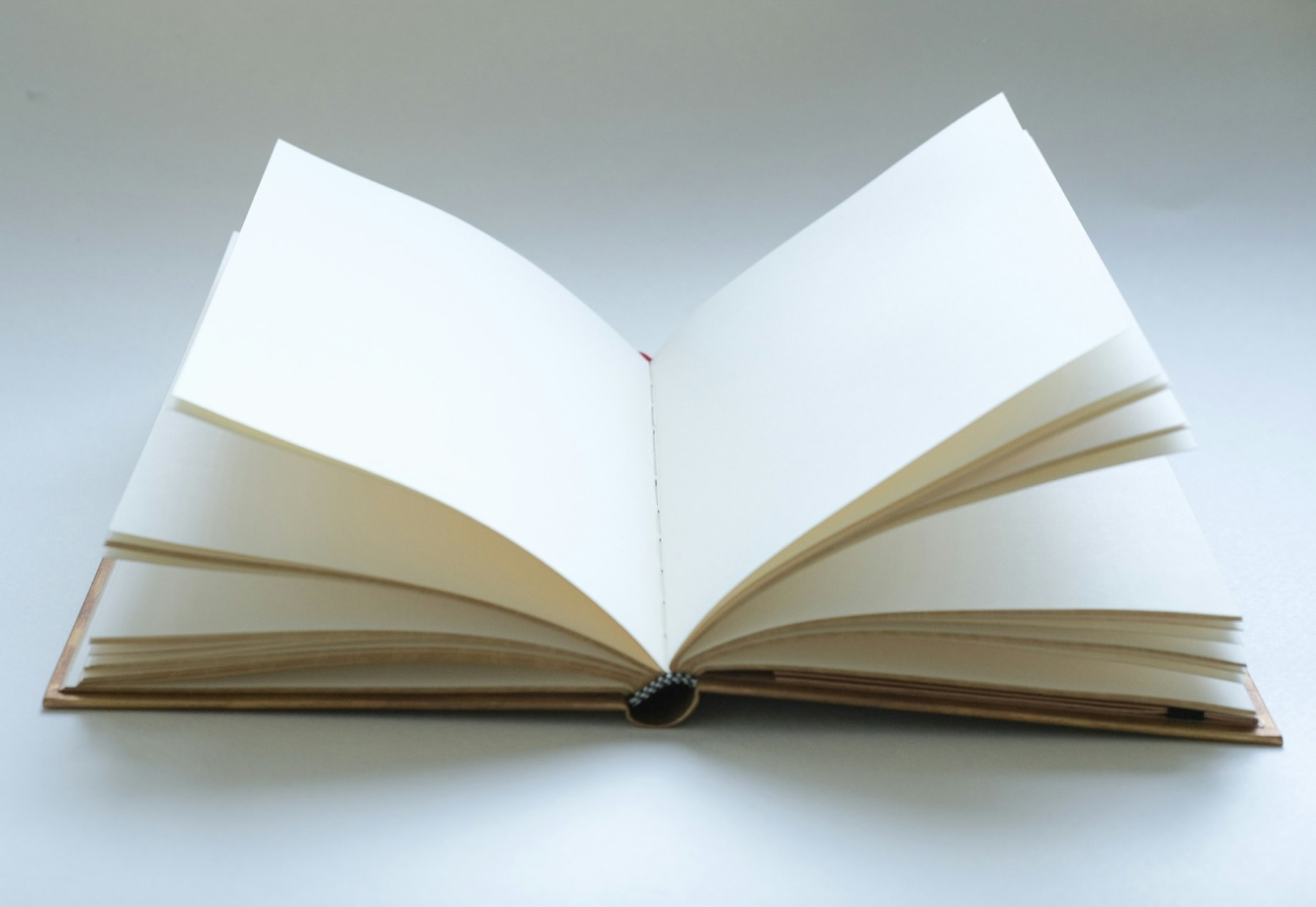 A blank open book with empty cream pages on a pale grey surface
