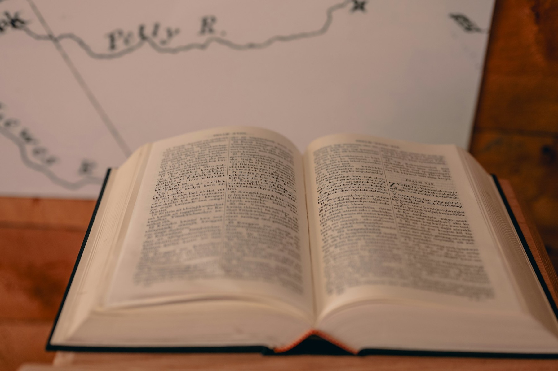 An open book printed in several languages sits in front of a printed map