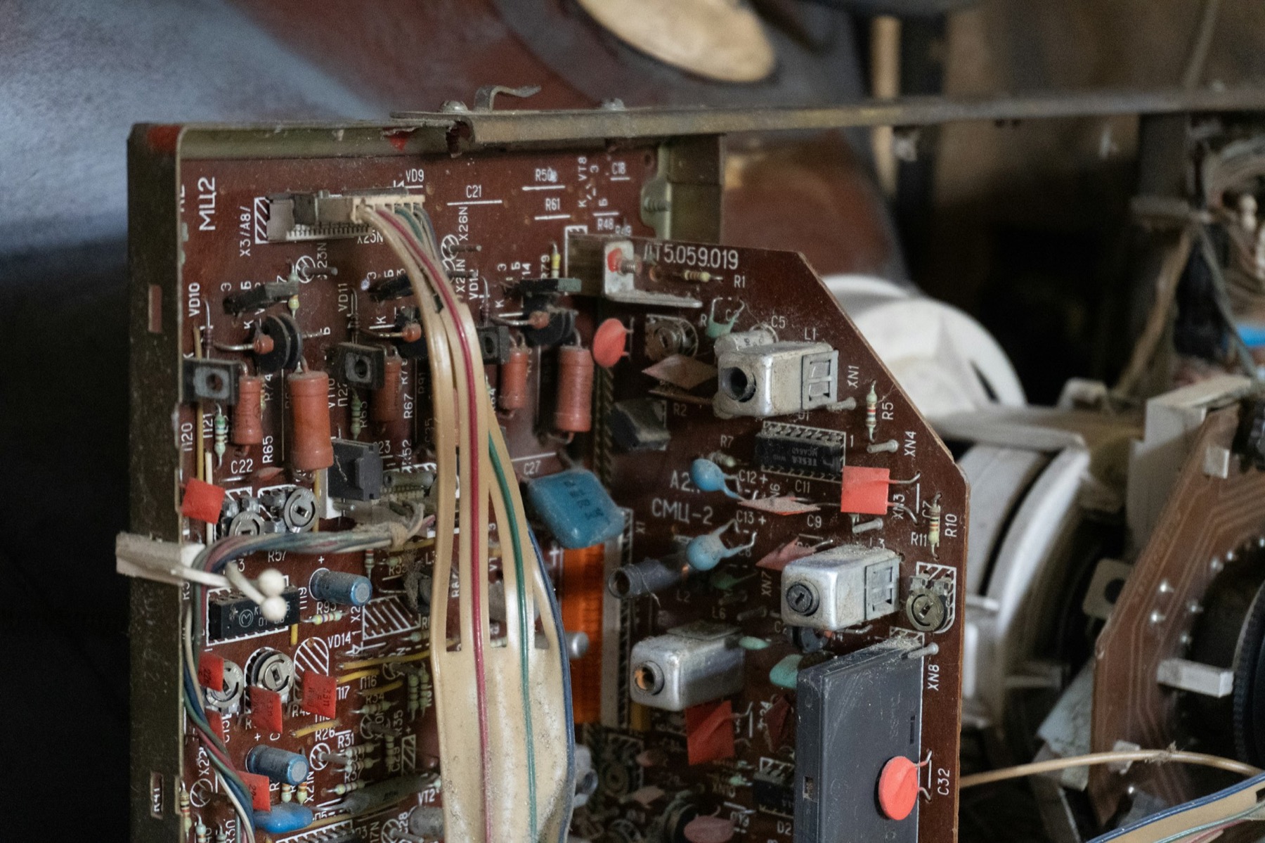 Close-up of an old circuit board with wires and capacitors inside a dismantled electronics unit
